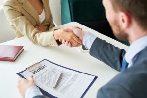 Two people shaking hands over a contract